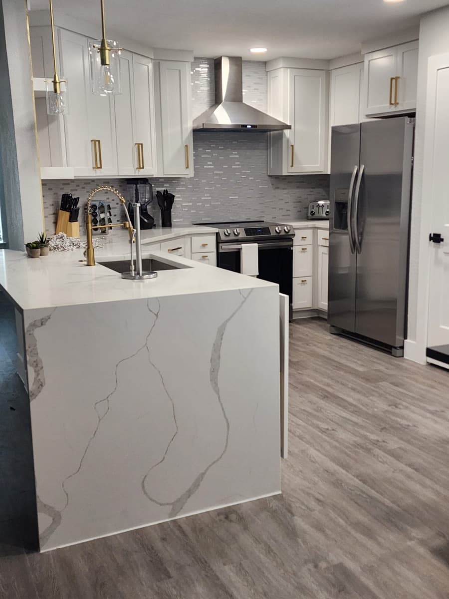 Carrillo Innovations finished kitchen with a marble waterfall island and gold fixtures